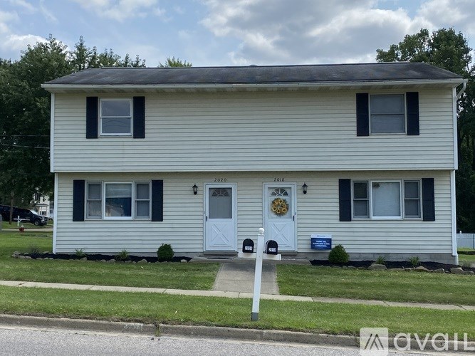 A two-story house with a white front door and black shutters.