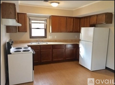 A kitchen with white appliances and wooden cabinets.