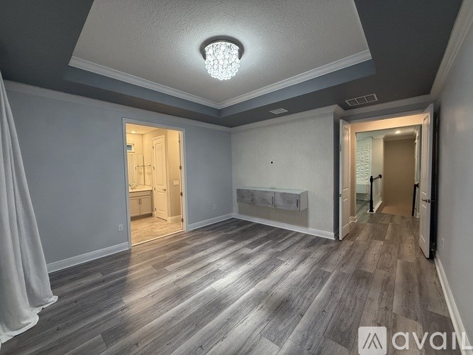 A spacious room with wooden flooring and a chandelier.