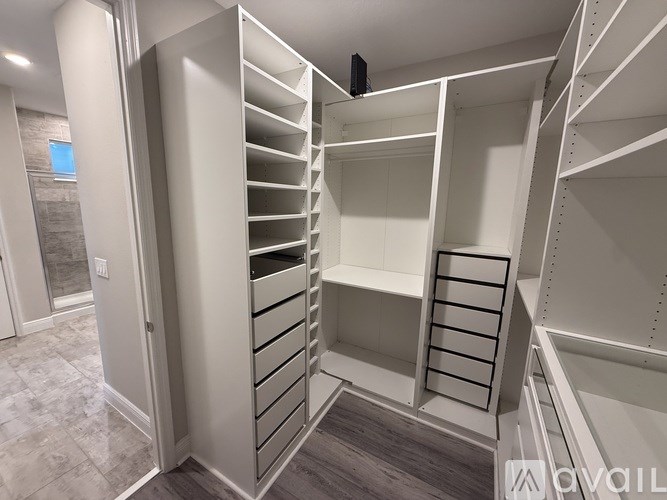 A walk-in closet with white shelving and drawers.