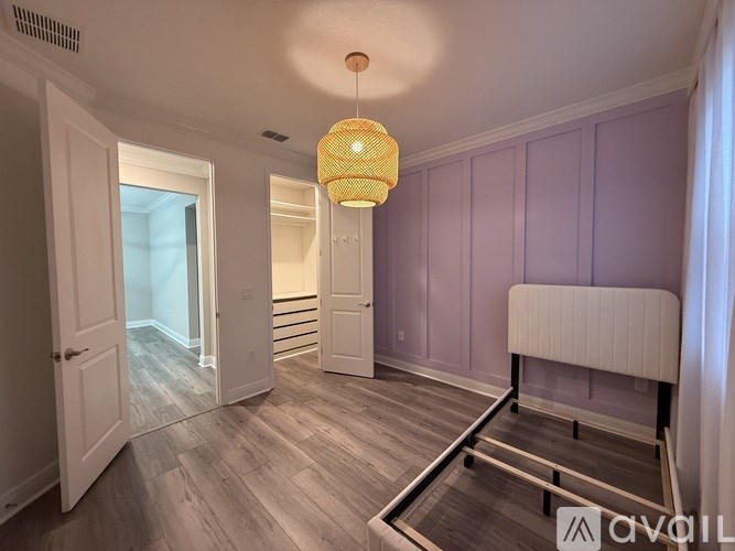 A room with a white door, a white bench, and a light hanging from the ceiling.