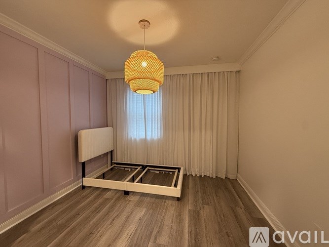 A room with a bed and a hanging light fixture.