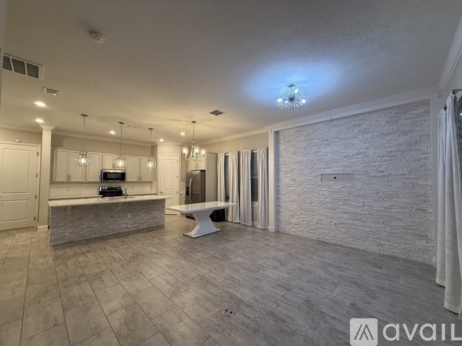 A spacious living room with a kitchen area in the background.