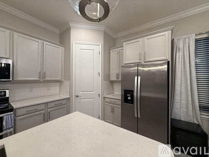 A kitchen with white cabinets and a stainless steel refrigerator.