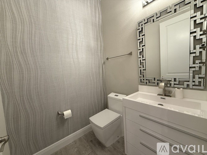 A bathroom with a toilet, sink, and mirror.