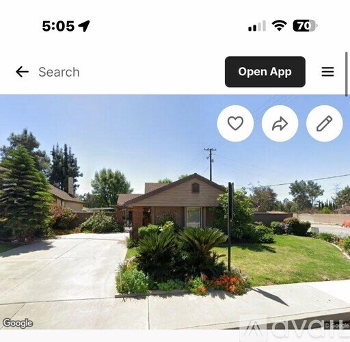 A house with a driveway and greenery in front.