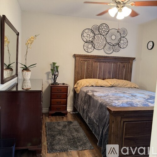 A bedroom with a bed, dresser, and ceiling fan.