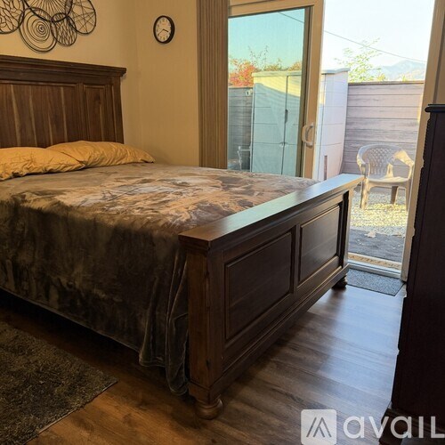 A bedroom with a bed, wooden headboard, and a window overlooking a backyard.