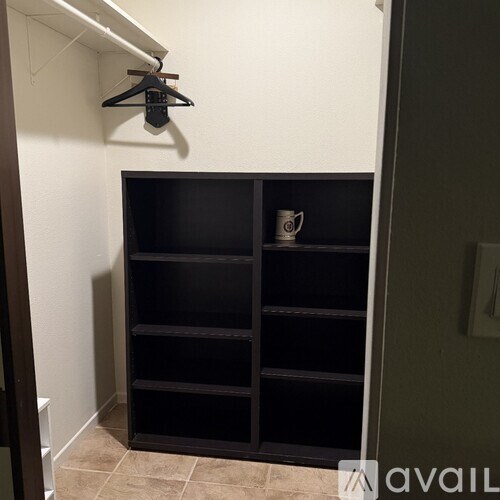 A black shelf with a hanger and a mug on it.