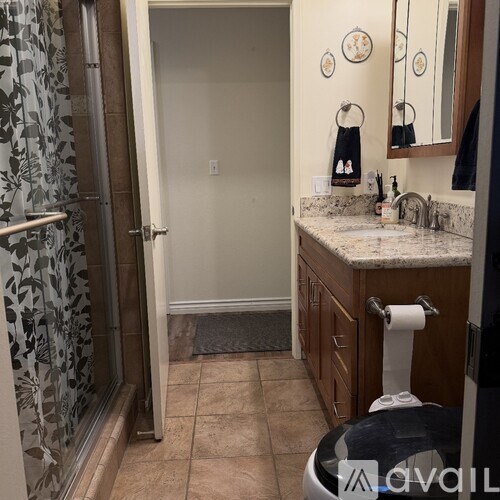 A bathroom with a white door, a sink, a mirror, and a shower with a floral shower curtain.