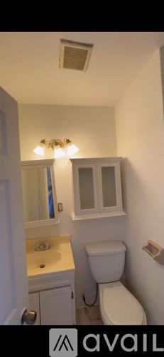 A small bathroom with a toilet, sink, and mirror.