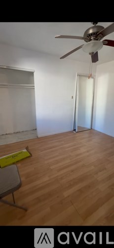 A room with a ceiling fan and wooden flooring.