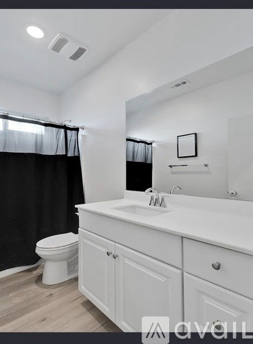 A white bathroom with a toilet, sink, and mirror.