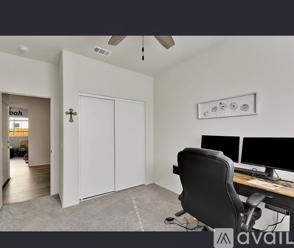 A room with a desk, chair, and a ceiling fan.