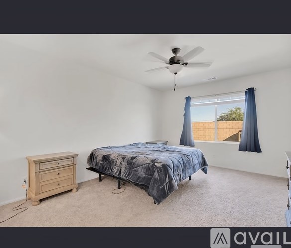 A bedroom with a bed, dresser, and window with a view of a fence.