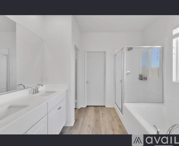 A white bathroom with a sink, mirror, and shower.