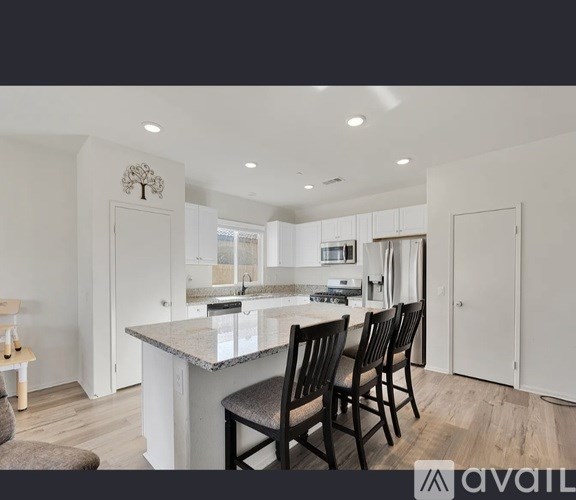 A modern kitchen with a large island and chairs.