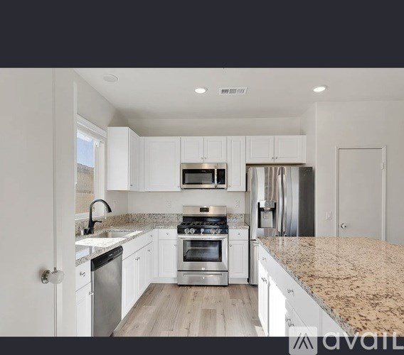 A modern kitchen with granite countertops and stainless steel appliances.