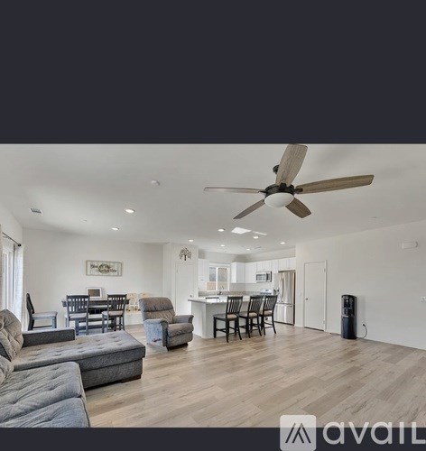 A spacious living room with a grey sofa and a dining area with a table and chairs.