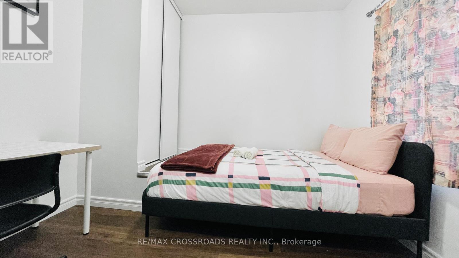 A bedroom with a bed, a table, and a chair.