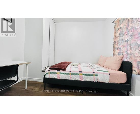 A bedroom with a bed, a table, and a chair.