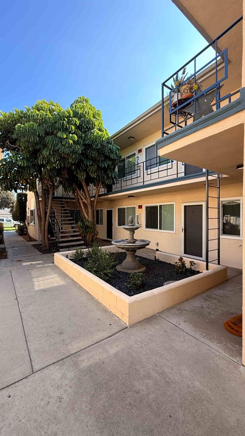 A building with a balcony and a tree in front.
