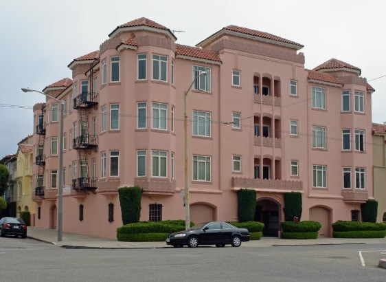 A pink building with a car parked in front.