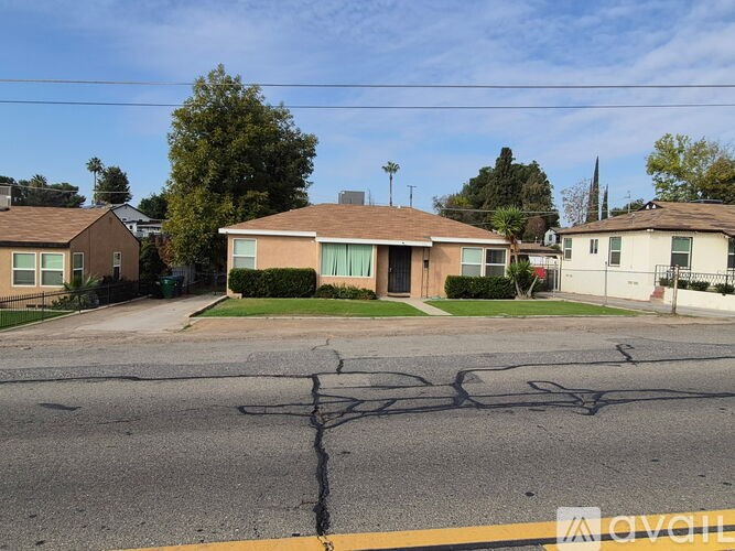 A residential street with houses on both sides and a cracked road.