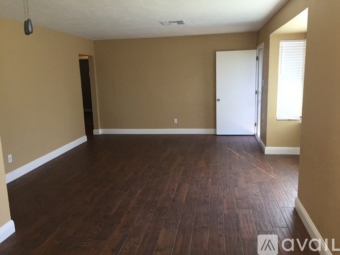A room with wooden flooring and a door on the right side.