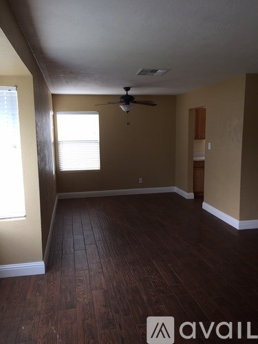 A room with a ceiling fan and wooden flooring.