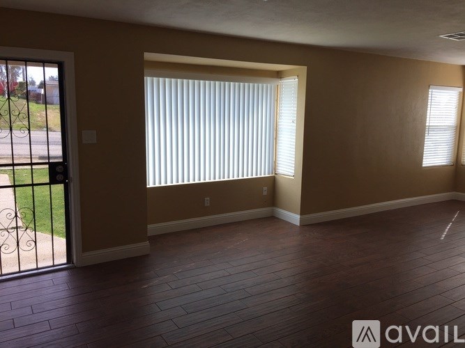 A room with brown walls and a wooden floor with a sliding glass door.