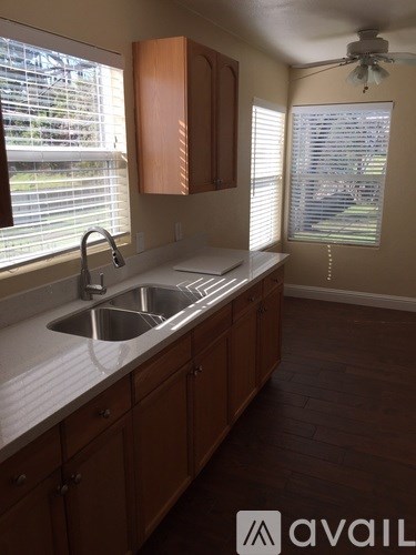A kitchen with wooden cabinets and a sink under a window.