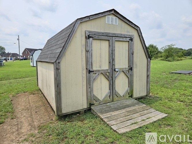A small wooden shed with a slanted roof and a door with a window above it.