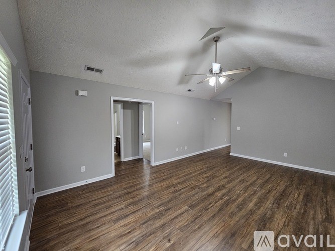 A spacious room with wooden floors and a ceiling fan.