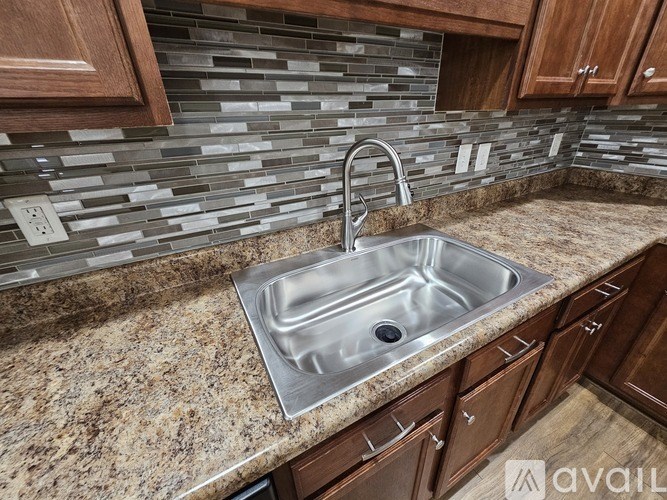 A kitchen with a granite countertop and a stainless steel sink.