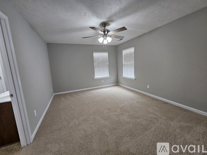 A room with a carpet floor and a ceiling fan.