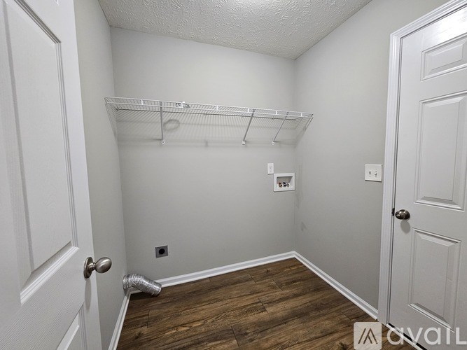 A white closet with a shelf and a white door.