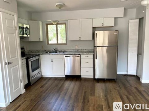 A kitchen with white cabinets and a wooden floor.