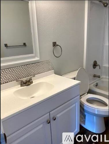 A bathroom with a toilet, sink, and mirror.