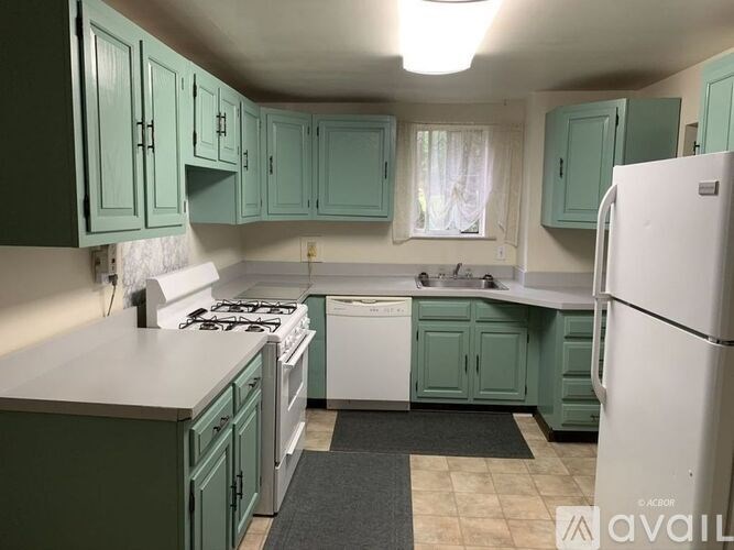 A kitchen with green cabinets and a white refrigerator.