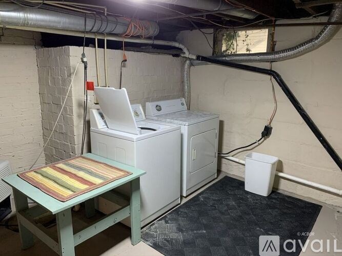 A laundry room with a washer and dryer, a table, and a rug.