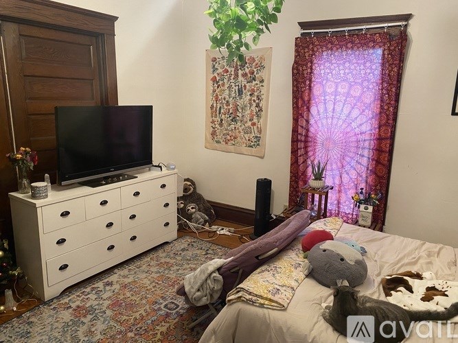 A room with a bed, a dresser, a TV, and a window with curtains.