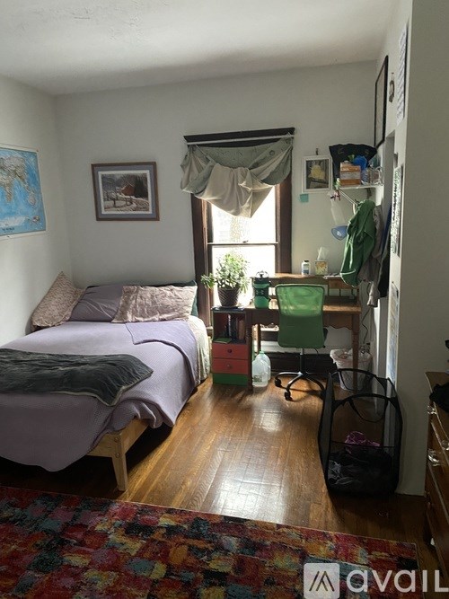 A bedroom with a bed and a desk with a chair.