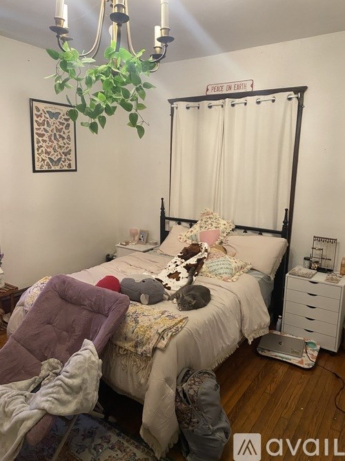 A bedroom with a bed, chair, and a chandelier.