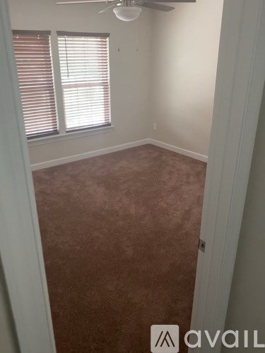 A room with a fan and a window with blinds.