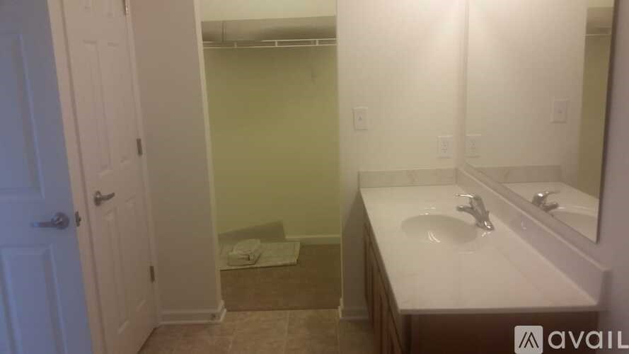 A bathroom with a sink, mirror, and towel on the floor.