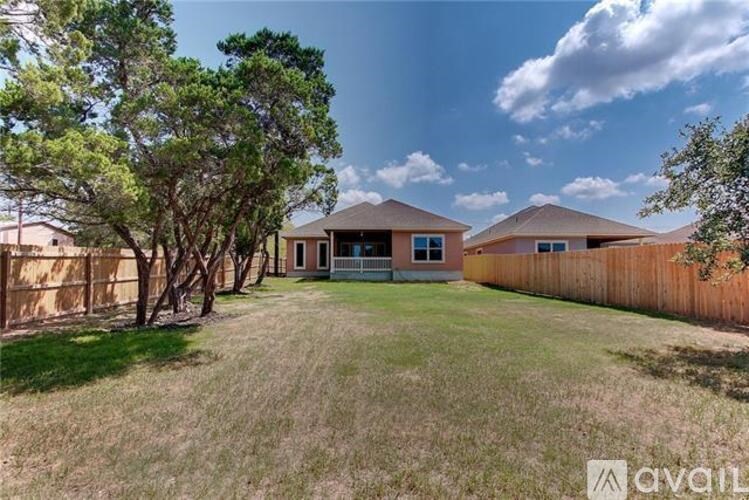 A house with a brown fence and trees in front of it.