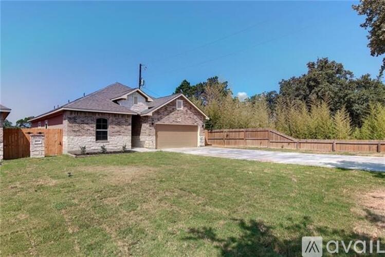 A house with a brown roof and a garage is surrounded by a grassy area.