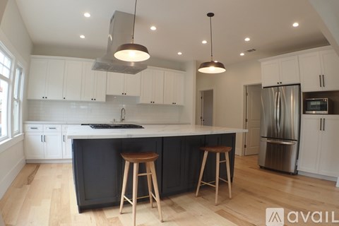 A kitchen with white cabinets and a black island.