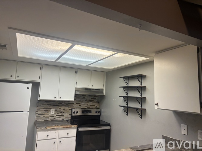 A kitchen with white cabinets and a stone backsplash.